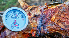 A SpitJack Dual Sensor Meat and Oven Thermometer is attached to a piece of meat.