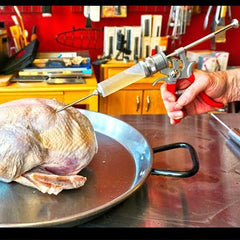 A person is using the SpitJack Magnum Meat Injector Gun - Complete Kit with Padded Soft Case on a turkey.