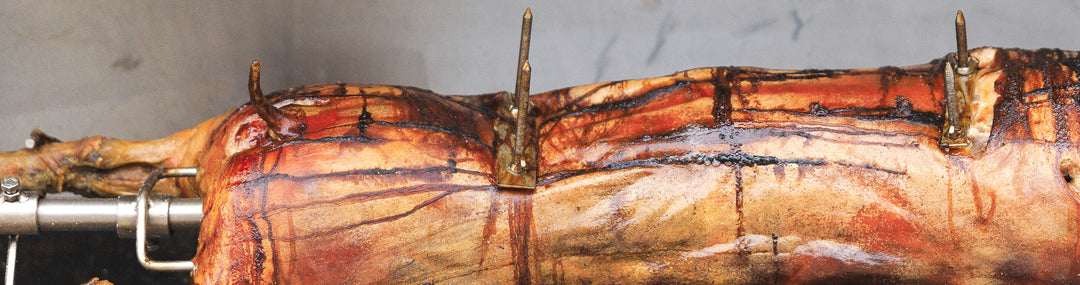 A large piece of meat being cooked on a SpitJack Stainless Rotisserie Trussing U-Bolt - 8" (2 Pack) grill.