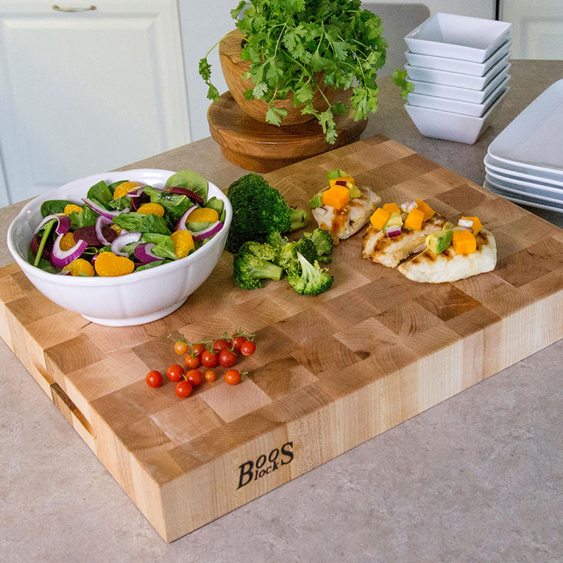 The John Boos Boos Block CCB Series Large Reversible Wood Chopping Board, featuring a 2.25-inch thickness and dimensions of 20" x 15" x 2 1/4", is crafted from maple wood. This rectangular board, branded with the iconic Boos Block logo on one side, offers a patterned surface and a handle groove on the shorter end, making it perfect for your kitchen or elegant gatherings.