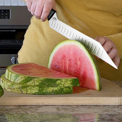A person in a yellow shirt slices a watermelon with the SpitJack BRSKT 2.0S Brisket Slicing Knife by SpitJack on a wooden cutting board.