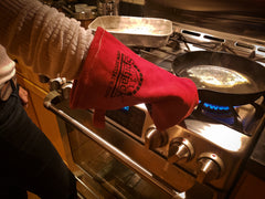 A person wearing a red SpitJack Deluxe Fireplace - Barbecue Gloves FP.