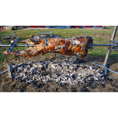 A pig is being cooked on a SpitJack Rotisserie Spit Leg Shackles for 1 inch Spits in a field.