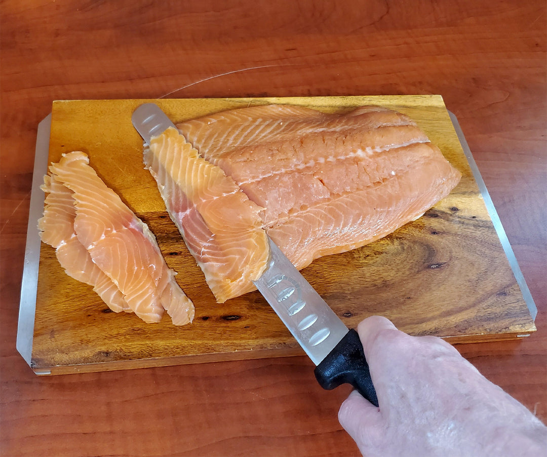 A person expertly slicing a salmon fillet with a SpitJack chef&