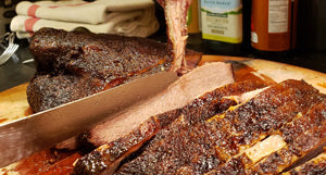 A person is slicing a piece of SpitJack Brisket, Ham, Turkey Carving and Carving Knife - 11 inch blade on a cutting board.